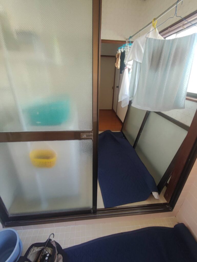 浴室引き戸を取り外して戸車交換作業を行う様子