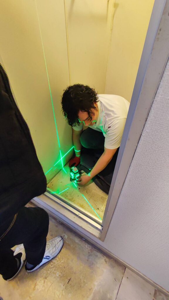 浴室ドア交換でレーザーを使い建付けを確認している様子