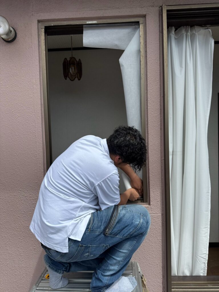 清掃した既設窓枠に気密シートを貼って防水処理している様子