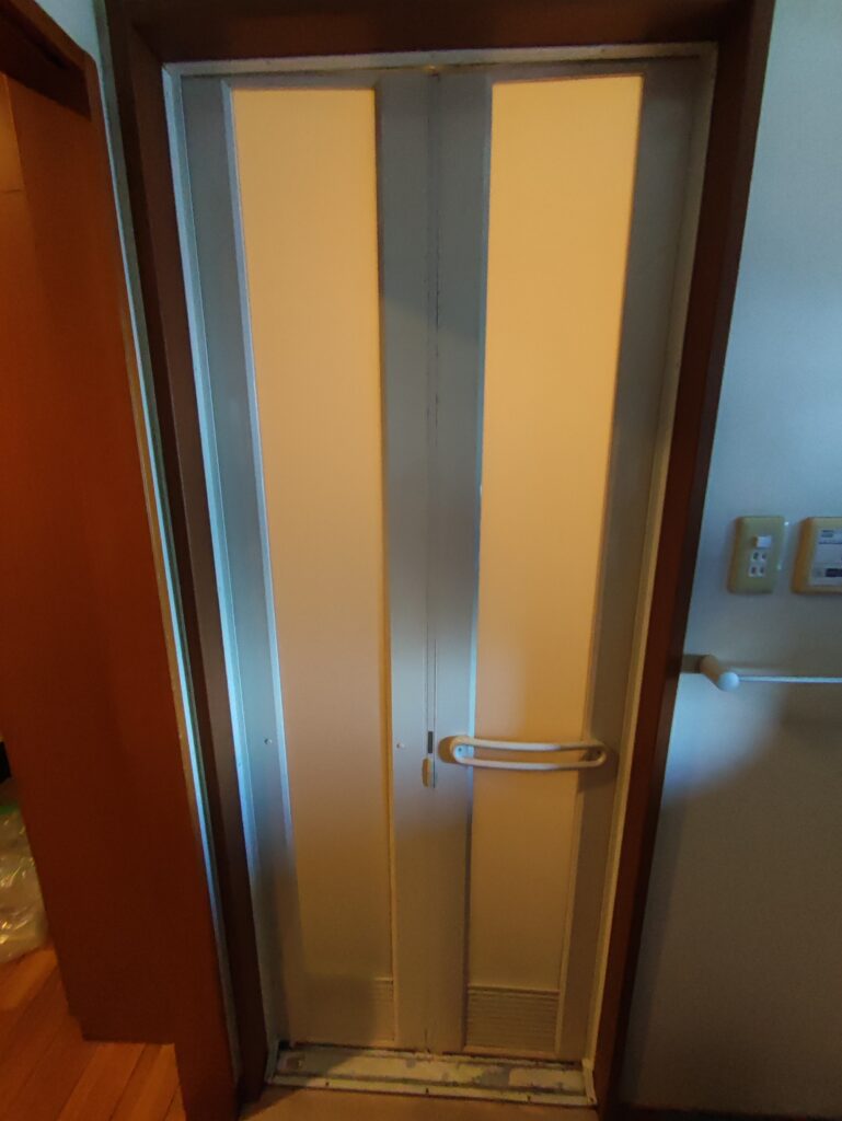 宇部市草江の浴室ドア交換前 脱衣場側の下アングルに腐食と塗装剥がれがある状態